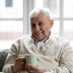 Senior investor holding a cup, symbolizing experience in AI chatbot investment and ESG analysis