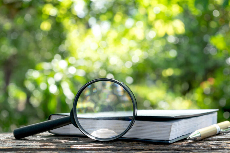 Magnifying glass on a book, representing tools for deep ESG data analysis and AI chatbot investment